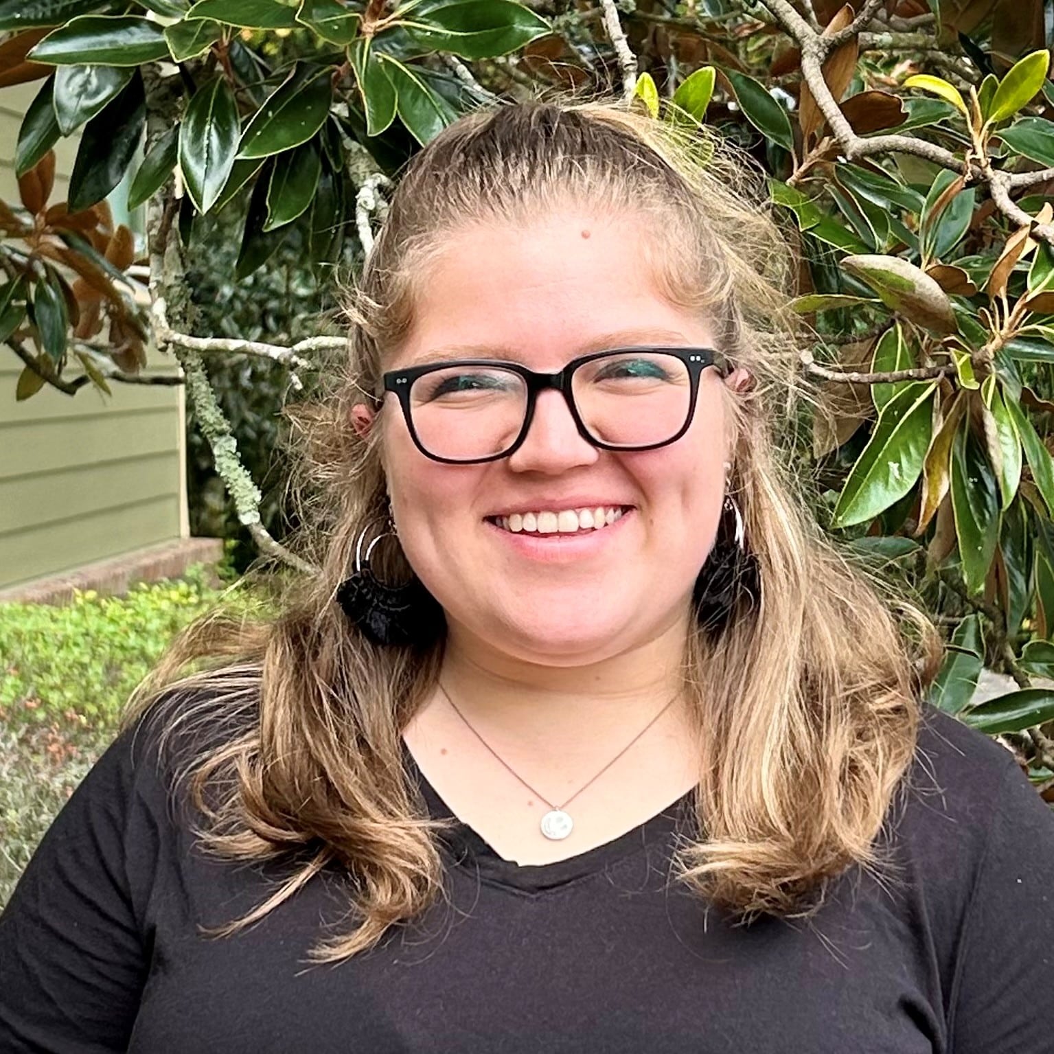 a person wearing glasses and smiling at the camera